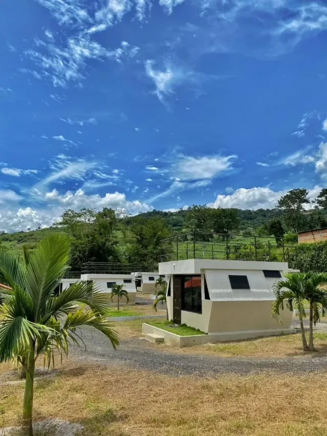 Suites hexagonales de glamping Bucaramanga rodeadas de montañas, palmeras y cielo azul despejado.
