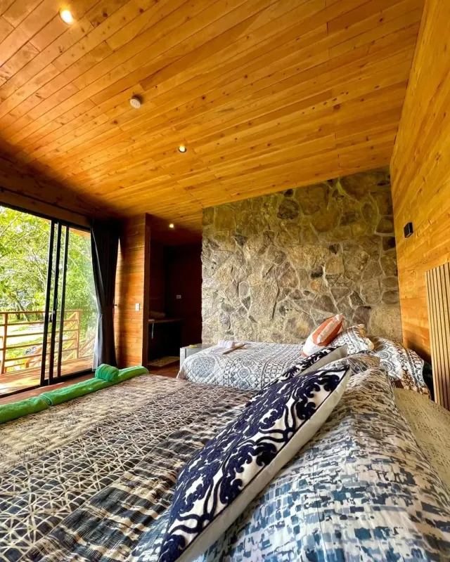 Habitación de cabaña de glamping en madera con camas dobles y ambiente cálido