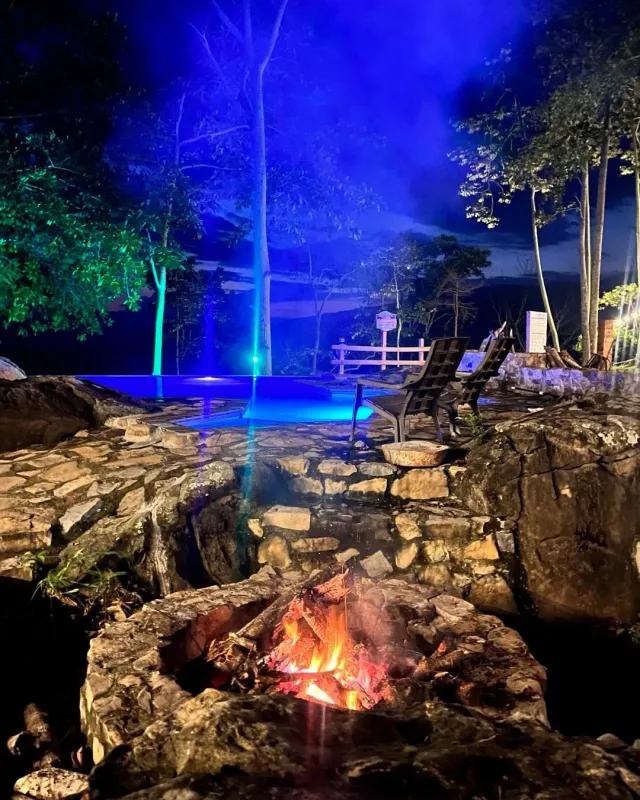 Piscina iluminada al atardecer entre árboles, experiencia de glamping Bucaramanga con piscina y entorno natural tranquilo.