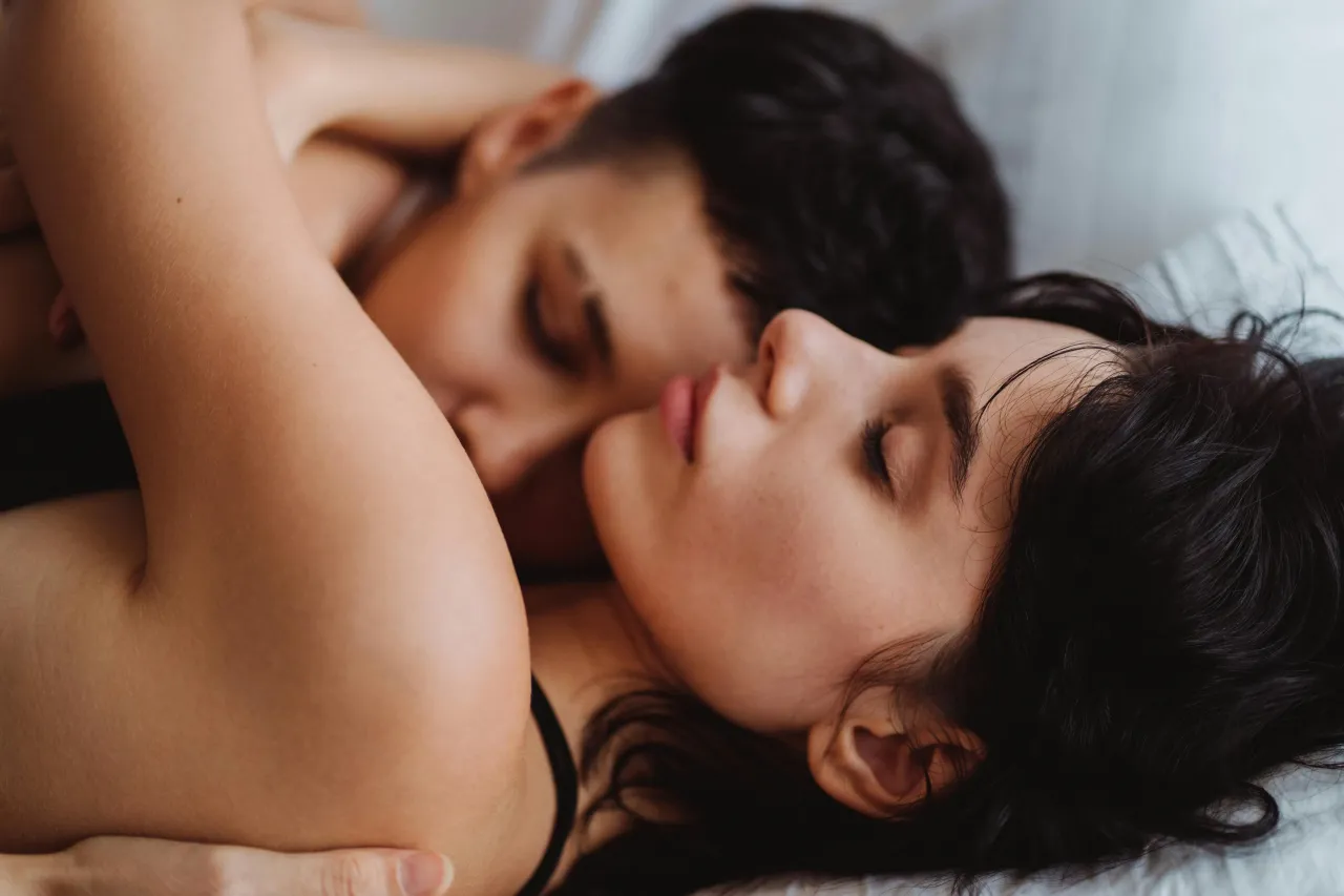 Pareja abrazada en la cama en un momento íntimo, reflejando conexión emocional y juegos en pareja en ambiente relajado